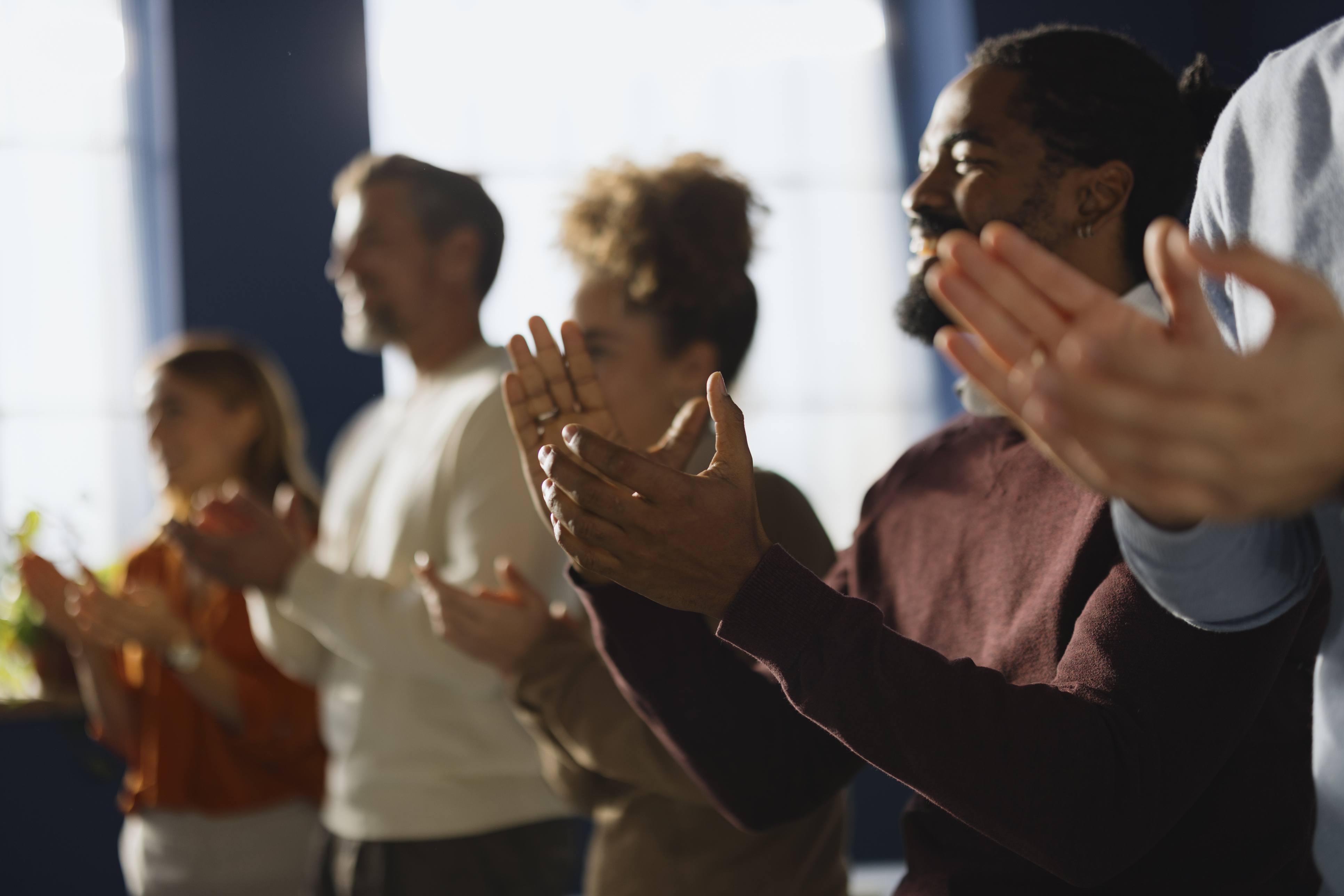 Grupo de personas aplaudiendo, simbolizando el reconocimiento y las expectativas positivas asociadas al impacto del efecto Pigmalión