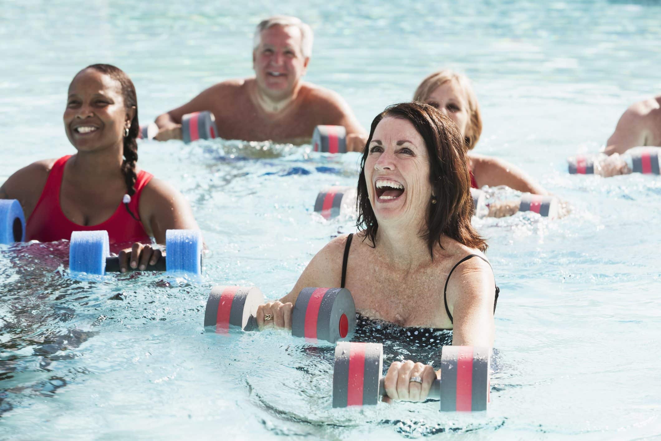 Grupo de personas divirtiéndose realizando ejercicios en la piscina durante una clase de aquagym