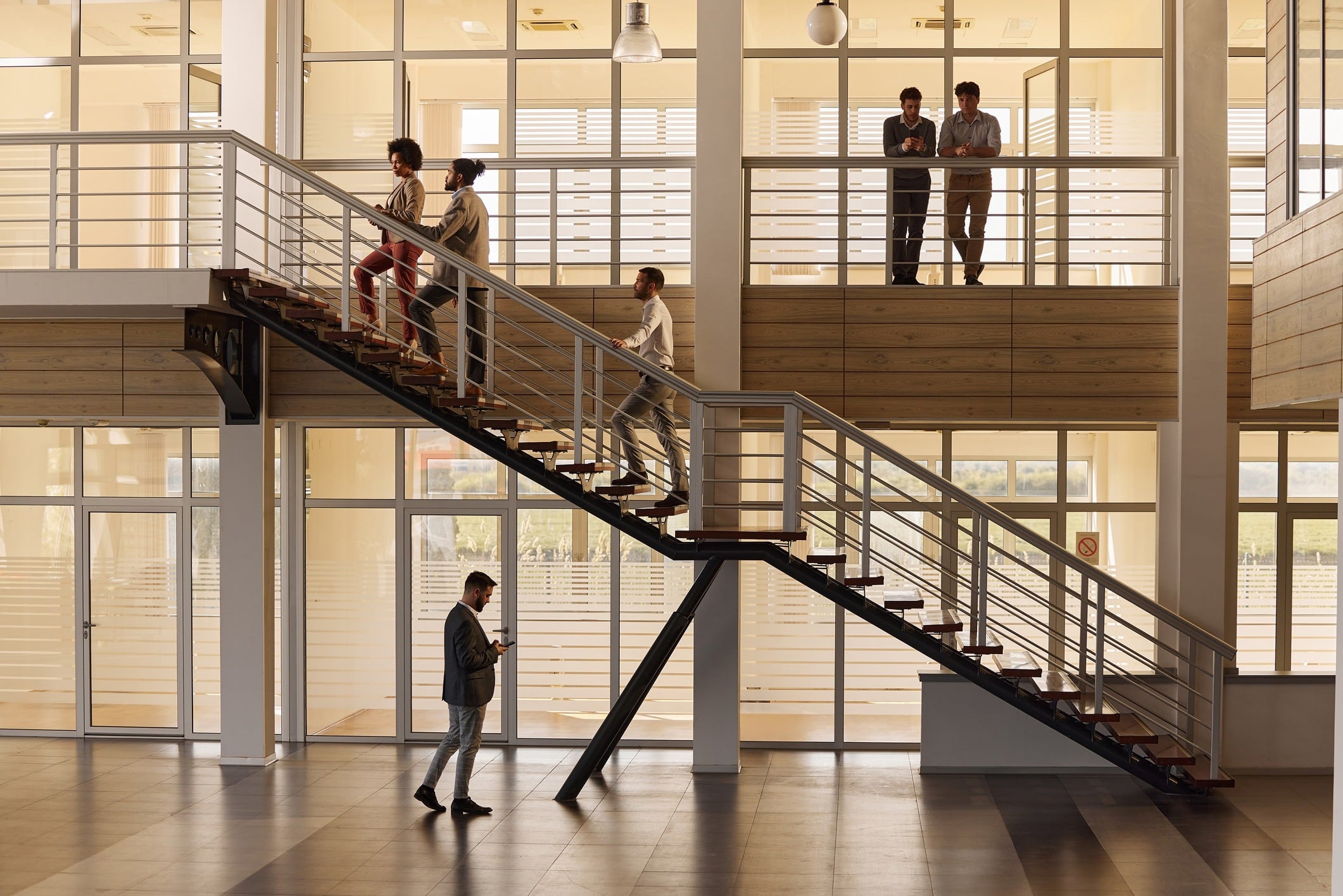 Grupo de empleados subiendo escaleras en una oficina, siendo ejemplo de los grandes beneficios de subir escaleras todos los días en el trabajo