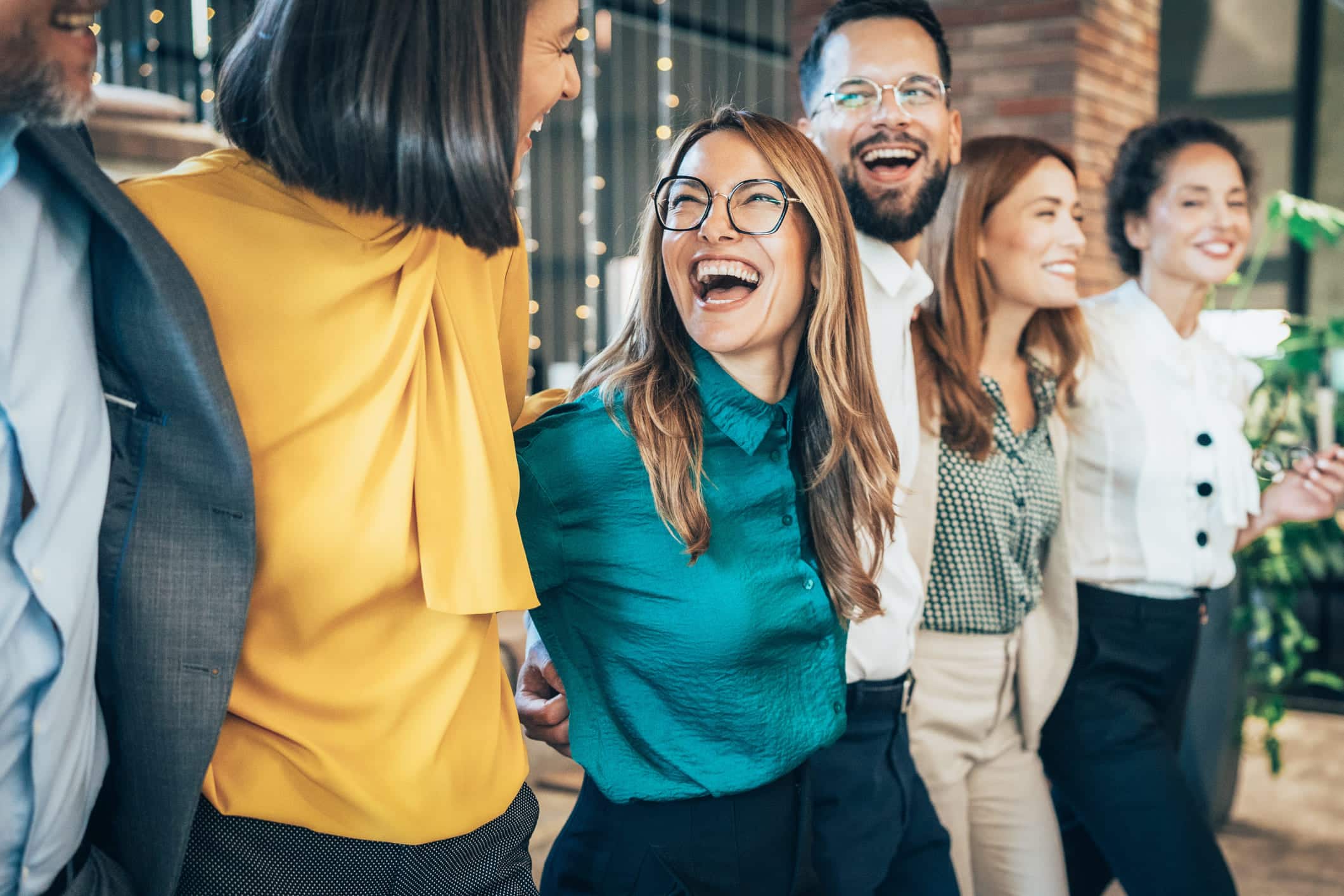 Grupo de empleados sonrientes en la oficina, reflejando un ambiente laboral positivo y de bienestar corporativo, clave para la salud mental en el trabajo.