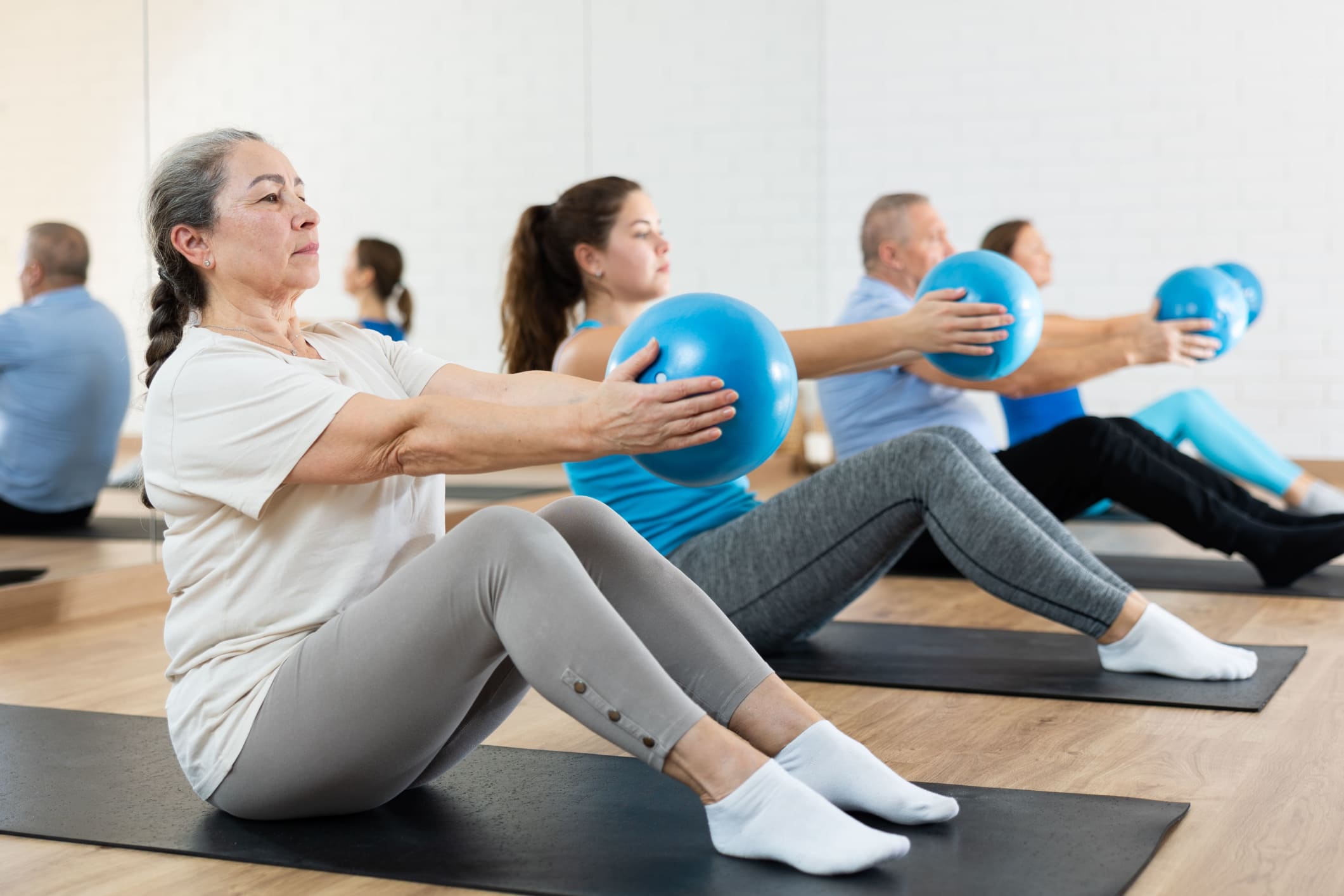 Grupo de personas en una clase de pilates usando la soft-ball para mejorar su fuerza y postura.