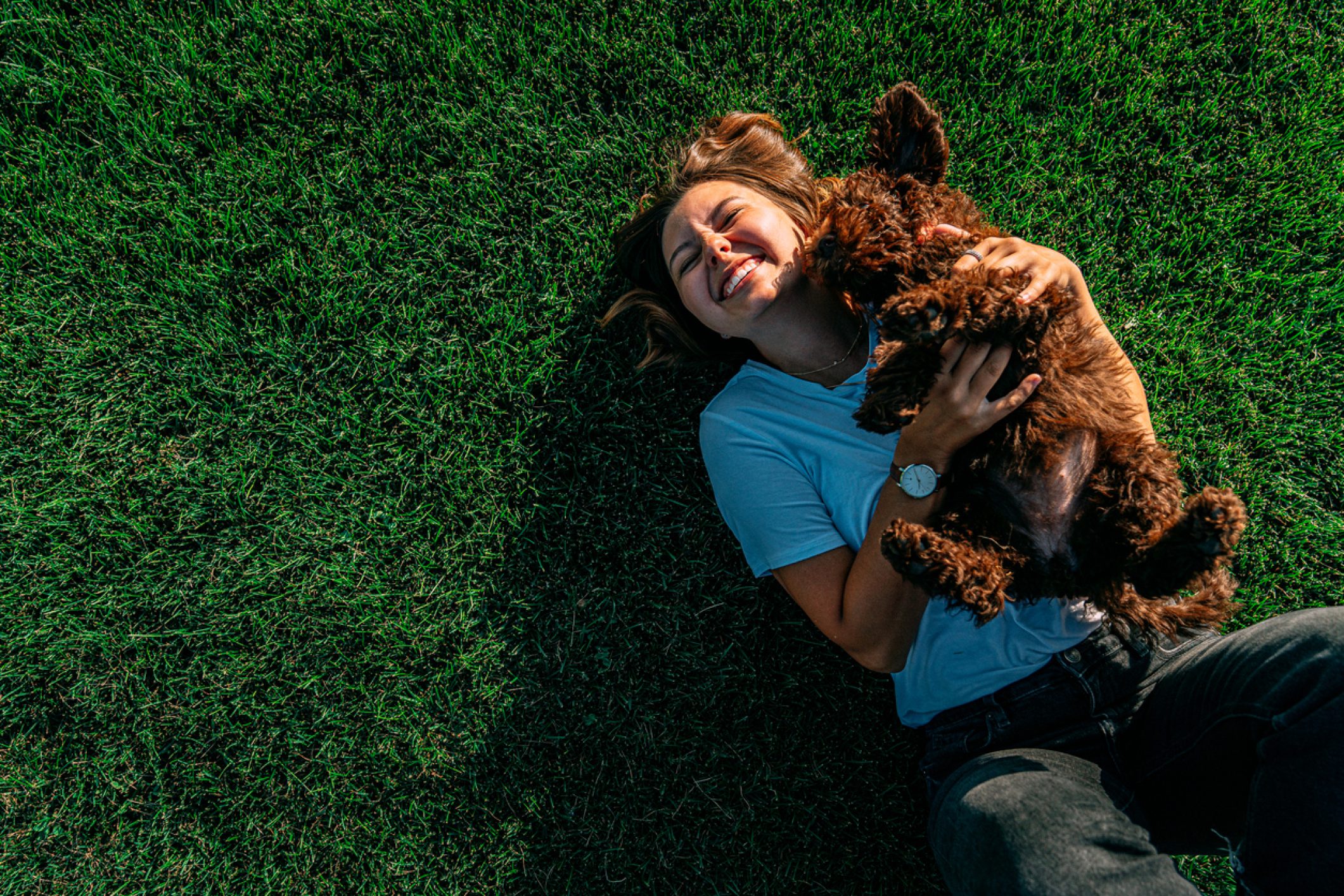 Mujer disfrutando de un momento de bienestar al aire libre con su perro, relajándose sobre el césped