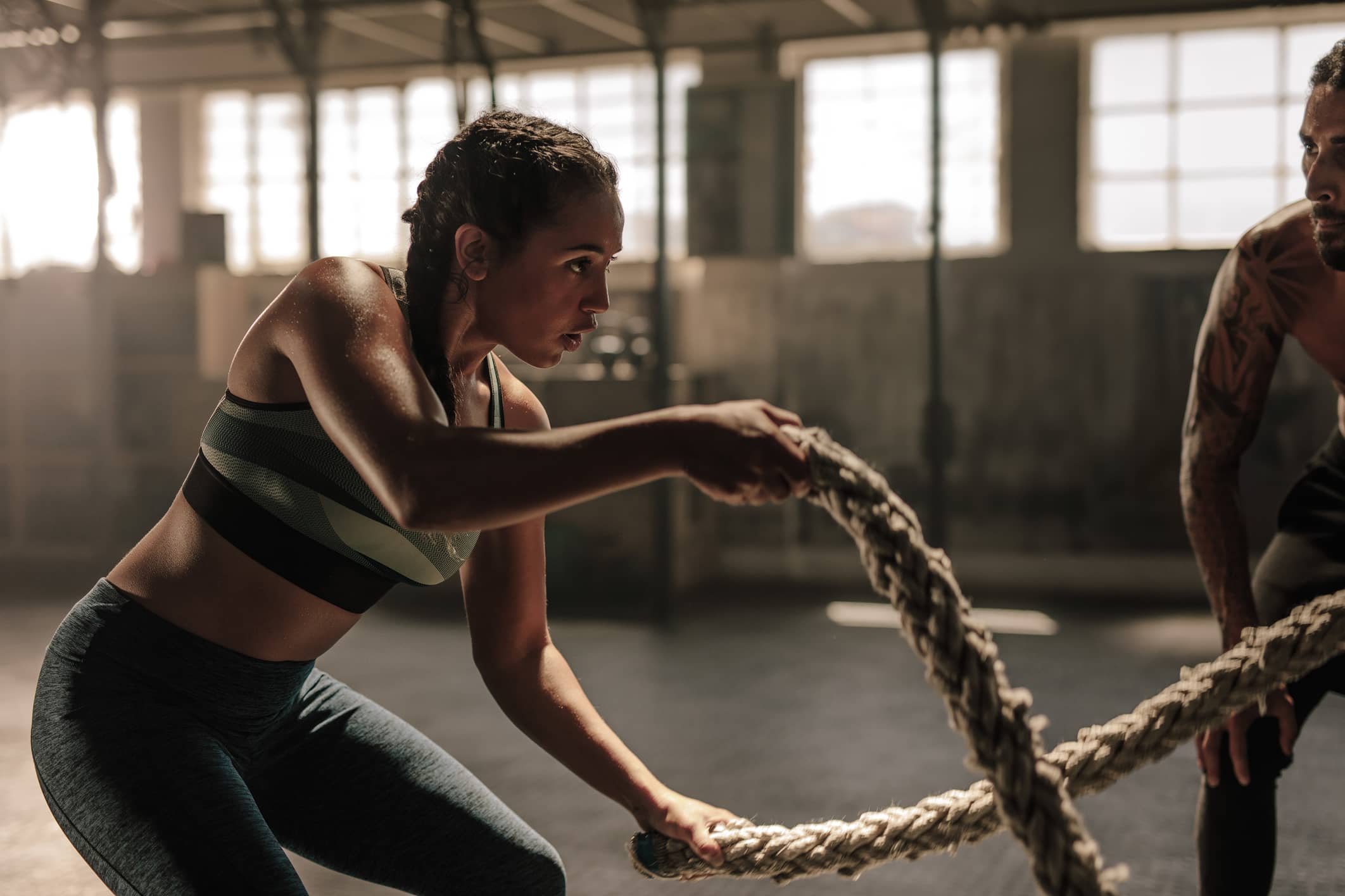 Mujer practicando CrossFit con cuerdas en un gimnasio.